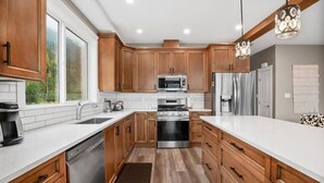 Una cocina moderna con armarios de madera, electrodomésticos de acero inoxidable y un amplio ventanal.