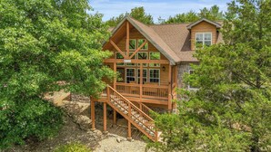 A log cabin with a wooden deck and stairs leading to a porch. - Rustic Cabin with 4 Master Suites by SDC! (Branson West)