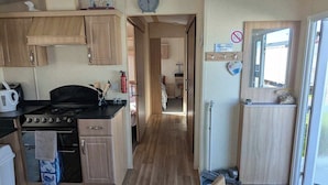 A compact kitchen with wooden cabinets, a stove, and a refrigerator. - ml Accessible Caravan in Ingoldmells Skegness (Skegness)