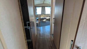 A hallway with wooden flooring leading to a dining area with a table and chairs. - ml Accessible Caravan in Ingoldmells Skegness (Skegness)
