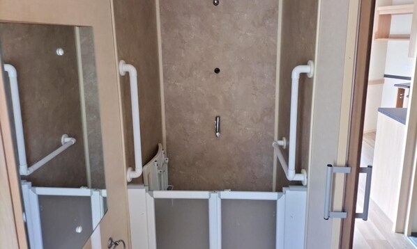 A bathroom with a shower area, a toilet, and a sink. - ml Accessible Caravan in Ingoldmells Skegness (Skegness)