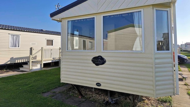 A small, single-story mobile home with a flat roof and a porch. It has two large windows and a small door. - ml Accessible Caravan in Ingoldmells Skegness (Skegness)