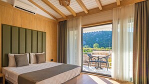 Un dormitorio con una cama grande, cabecera de madera y un ventanal corredero que da a un espacio exterior con una mesa y sillas.