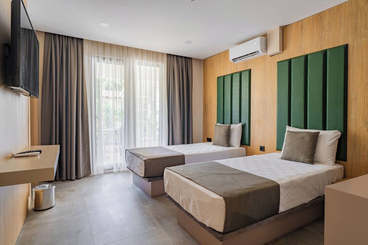Habitación de hotel con dos camas, un escritorio y un televisor.