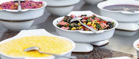 Diversos platos de comida en recipientes blancos sobre una encimera de mármol.