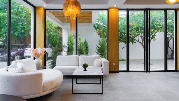 A modern interior with a white sofa, a round coffee table, and a hanging light fixture. - Perast Garden Hotel (Kemer)