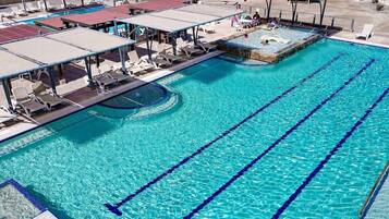 Une piscine avec plusieurs couloirs de nage, des chaises longues et des zones ombragées.