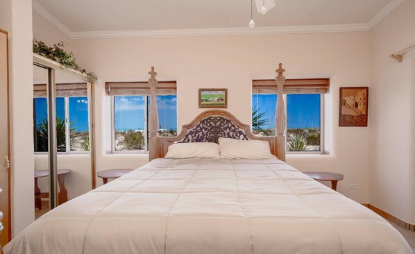 A spacious bedroom with a large bed, two bedside tables, and a canopy bed frame. - Casa Susie with communal heated pool. (San Felipe)