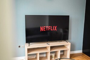 A television on a wooden stand with the Netflix logo displayed on the screen. - One Bedroom Flat in Gravesend Kent (Gravesend)