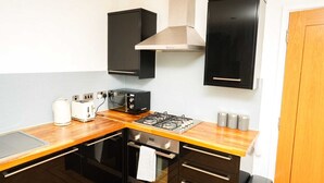 A compact kitchen with a gas stove, a microwave, a toaster, and cabinets. - One Bedroom Flat in Gravesend Kent (Gravesend)
