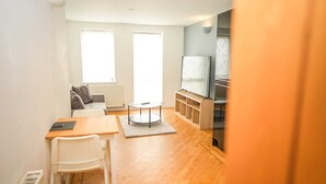 A modern living room with a sofa, a coffee table, a TV, and a fireplace. - One Bedroom Flat in Gravesend Kent (Gravesend)