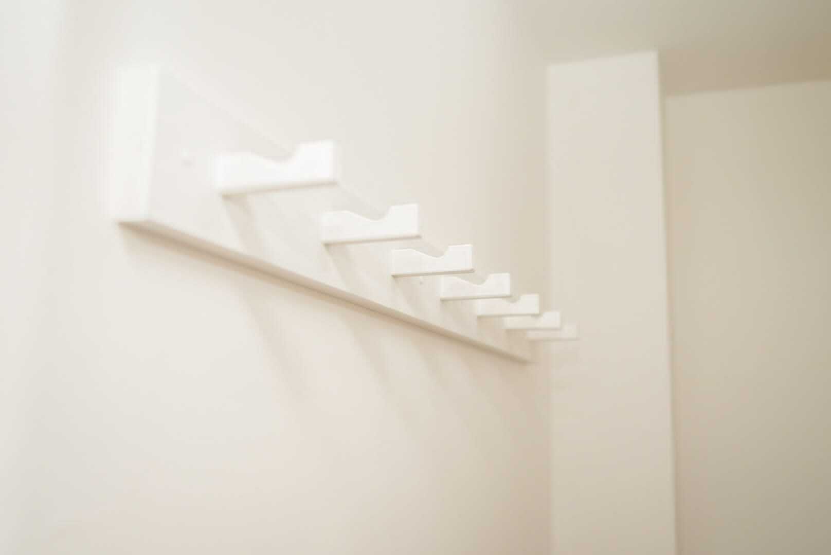A white wall with a series of white, rectangular objects arranged in a descending staircase pattern.