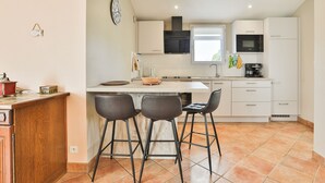 A compact kitchen with a central island, bar stools, and modern appliances. - Côte Vendéenne Résidence le pin Parasol (Longeville-sur-Mer)