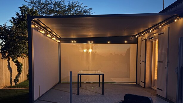 An outdoor patio area with a table and chairs, a covered seating area with string lights, and a view of the surrounding landscape. - Côte Vendéenne Résidence le pin Parasol (Longeville-sur-Mer)