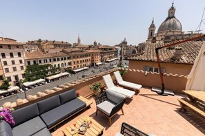 Eine Dachterrasse mit Außenbestuhlung und Blick auf eine Stadtlandschaft mit historischen Gebäuden und einer Kuppel.