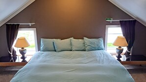 A bedroom with a large bed, two bedside lamps, a ceiling light, and a window with curtains. - Lónkot (Skagafjorour)