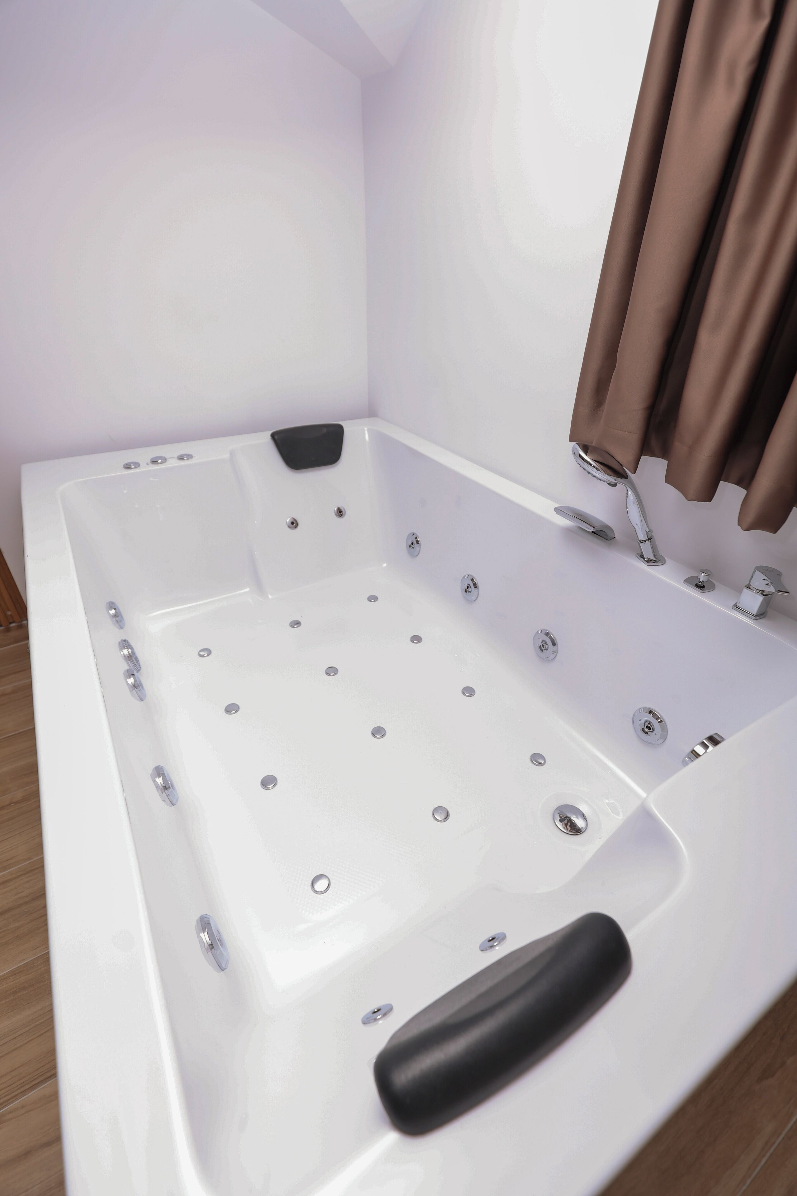 Una vasca da bagno bianca con getti idromassaggio, un rubinetto nero e una doccetta.