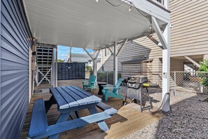 A covered patio area with a picnic table, two chairs, a barbecue grill, and a grill cart. - 10% off 3-7 nights thru Nov. Pet friendly home. 2nd Row. Cherry Grove. (North Myrtle Beach)
