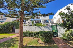 A residential area with white buildings, a tree, and a paved pathway. - Los Naranjos 15A (Nerja)