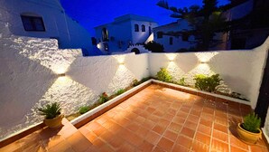 A courtyard with terracotta tiles, white walls, and potted plants. - Los Naranjos 15A (Nerja)