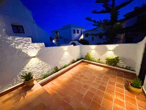 A courtyard with terracotta tiles, white walls, and potted plants. - Los Naranjos 15A (Nerja)