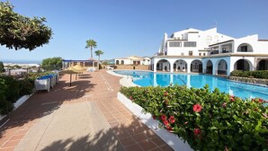 A resort with a swimming pool, white buildings, and a view of the sea. - Los Naranjos 15A (Nerja)