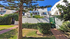 A residential area with white buildings, a tree, and a paved pathway.