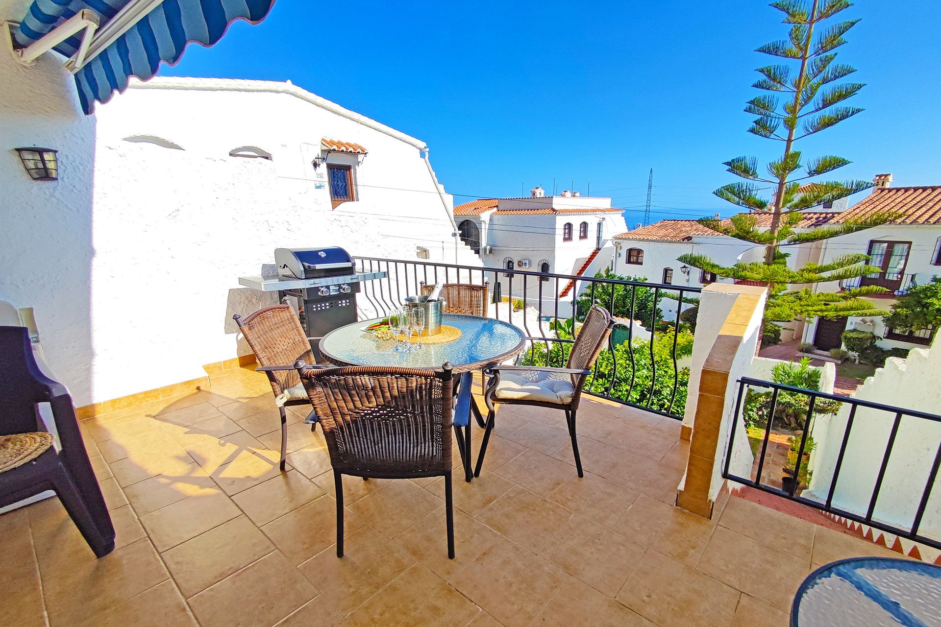 Un balcon avec une table ronde et des chaises, un barbecue et une vue sur le quartier.