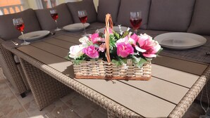 A wicker table with a woven basket containing pink and white flowers, set on a patio with a stone floor. - Ferienwohnung Direkt am Meer Erste Reihe Insel Vir 25km von Zadar (Vir)