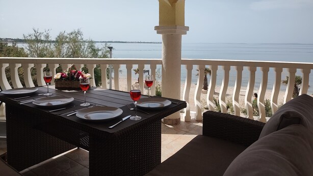 A terrace with a table set for dining, overlooking a body of water. - Ferienwohnung Direkt am Meer Erste Reihe Insel Vir 25km von Zadar (Vir)
