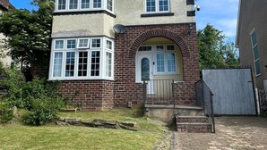 A two-story house with a brick facade, white-framed windows, and a central archway entrance.