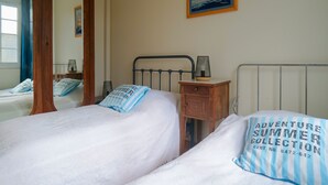 Un dormitorio con dos camas, un armario de madera, una mesita de noche con una lámpara y un cuadro en la pared.