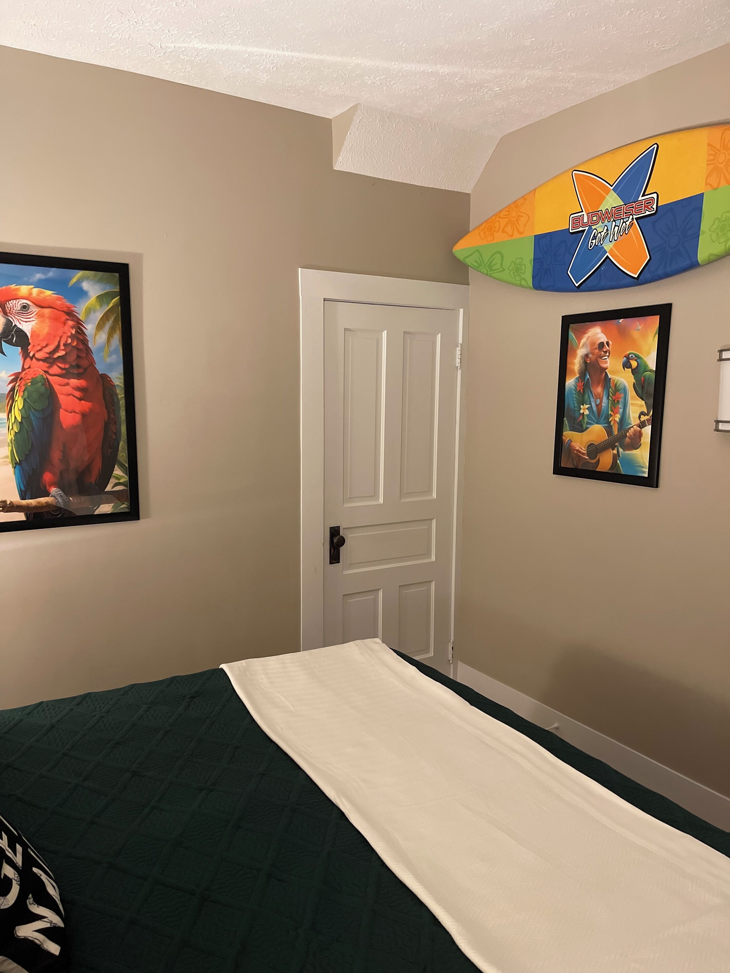 Une chambre à coucher avec un lit, une porte et deux tableaux encadrés accrochés au mur.