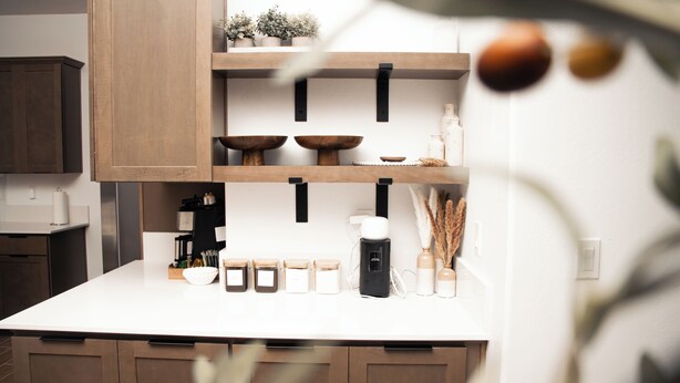 Une cuisine moderne avec des meubles en bois, un plan de travail blanc et divers ustensiles de cuisine.