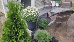 A house with a covered porch, outdoor seating, and various potted plants.