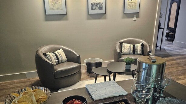 A room with two leather sofas, a coffee table, a tray of snacks, and framed pictures on the wall.