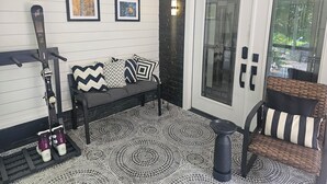 A corner room with a bench, a ski rack, and a door leading to a balcony.