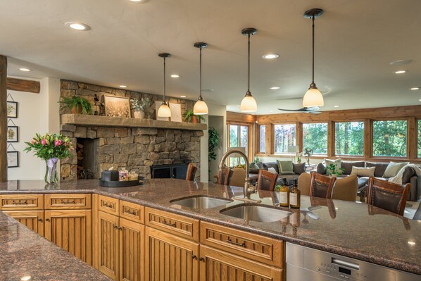 A kitchen with granite countertops, wooden cabinets, a stone fireplace, and pendant lighting. - 🏔️ Four Sisters Mountain Haven: Luxury, Hot Tub, Near Ski Lift & Village, $0 Cleaning & Pet Fee (Keystone)
