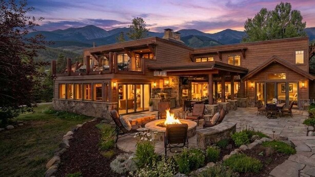 A two-story house with a stone fireplace, outdoor seating, and a view of mountains. - 🏔️ Four Sisters Mountain Haven: Luxury, Hot Tub, Near Ski Lift & Village, $0 Cleaning & Pet Fee (Keystone)