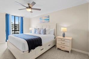 Ein Schlafzimmer mit einem Bett, Nachttischen, einem Deckenventilator und einem Bild an der Wand.