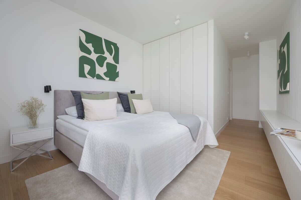 A modern bedroom with a bed, bedside tables, and a large mirror.