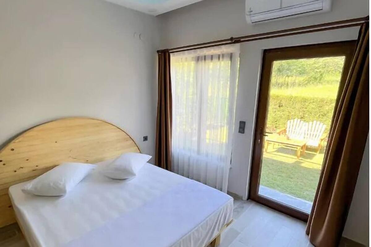 Habitación de hotel con cama, ventana con cortinas, aire acondicionado y vista al exterior.