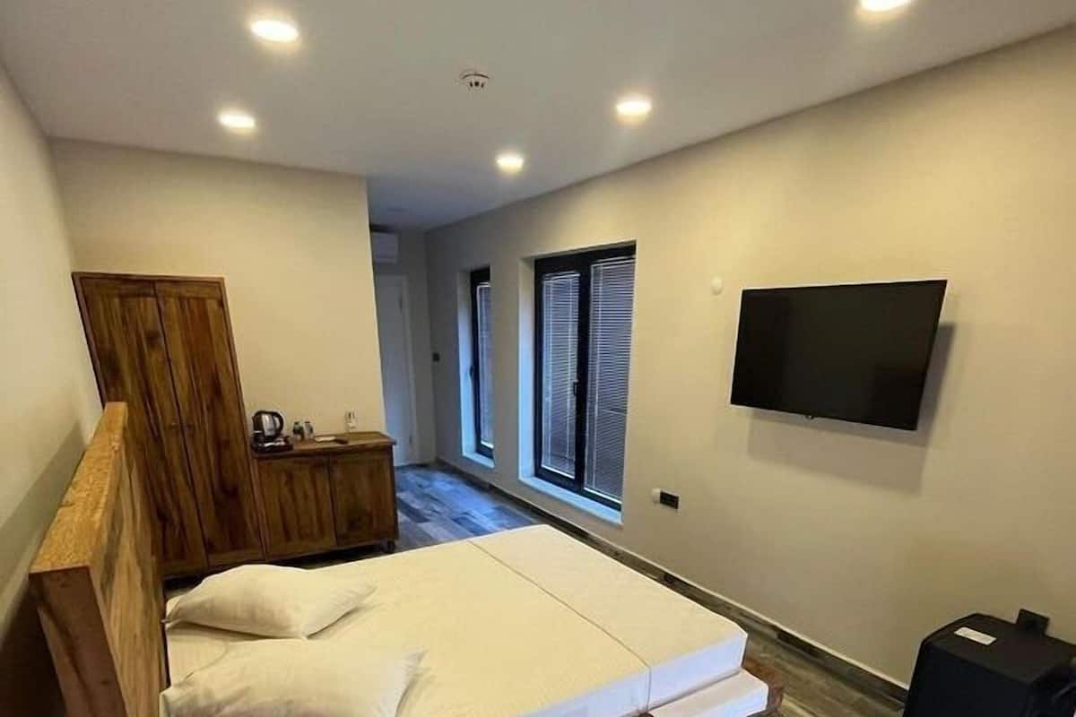 Un dormitorio moderno con una cama de madera, un televisor de pantalla plana y una mesita de noche.