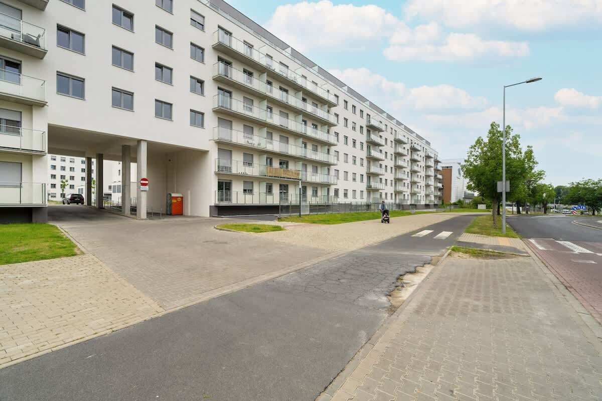 Un edificio residenziale a più piani con balconi, un ingresso chiuso da cancello e una strada privata lastricata.