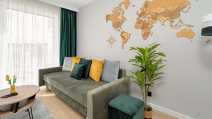 Una sala de estar moderna con un sofá gris, varios cojines, una mesa de centro redonda, un mapa del mundo en la pared y una planta en maceta.