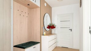 Una habitación con un armario de madera, un espejo, un banco y un aparador blanco con cajones.