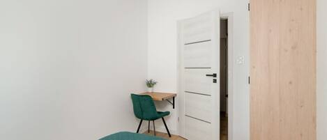 A bedroom with a bed, a desk, and a chair.