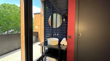 A modern bathroom with a large window, a round mirror, a sink, and a towel rack.