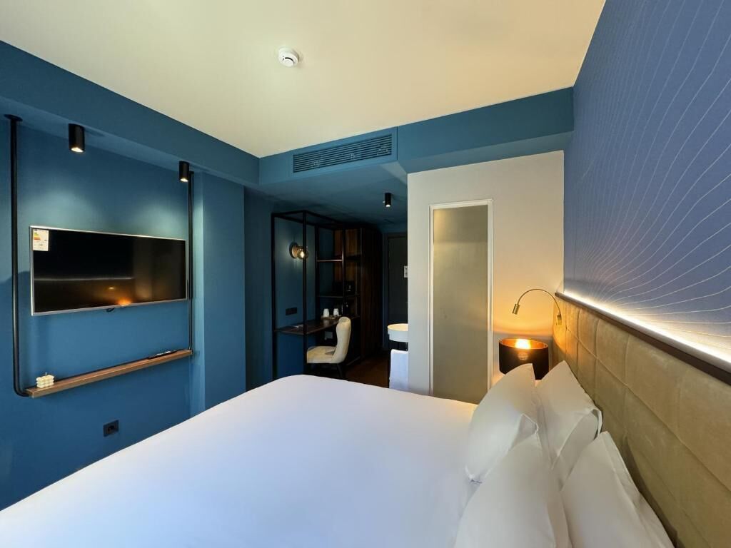 Une chambre d’hôtel avec un lit, une télévision, un bureau et une chaise.