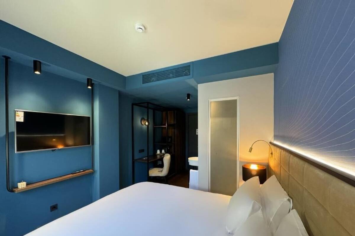 Une chambre d’hôtel avec un lit, une télévision, un bureau et une chaise.